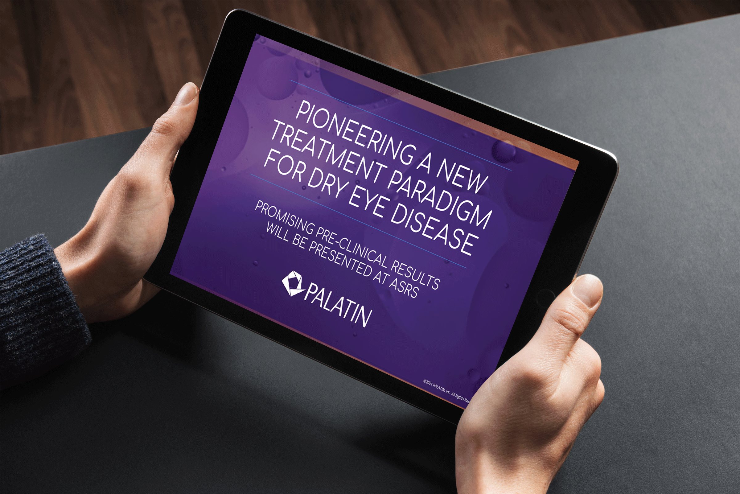 a closeup image of two hands holding a tablet with the screen showing the words 'pioneering a new treatment paradigm for dry eye disease' and the palatin logo